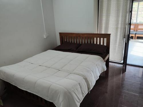 a bedroom with a bed with white sheets and a window at Armaan's mud mart in Kodaikānāl