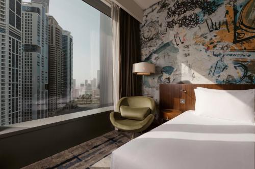 a hotel room with a bed and a chair and a window at Media One Hotel Dubai, WorldHotels Crafted in Dubai
