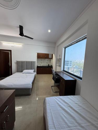 a bedroom with two beds and a desk and a window at Sukoon Stays in Noida