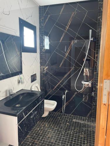 a black and white bathroom with a toilet and a sink at Villa Assef in Midoun
