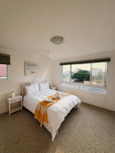 a white bedroom with a large bed and a window at Linga Longa in Britannia Bay