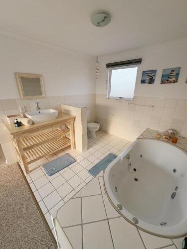 a bathroom with a tub and a sink and a toilet at Linga Longa in Britannia Bay