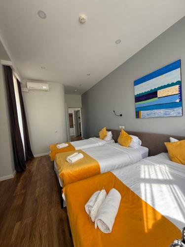 a room with three beds with orange and white sheets at Hotel Vista in Tbilisi City