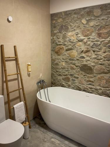 a bath tub in a bathroom with a stone wall at Quinta Casal de Bordeiro in Góis