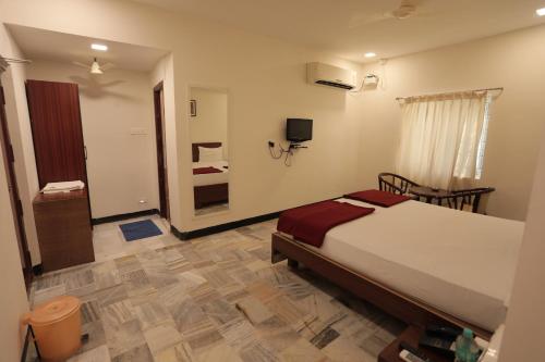 a bedroom with a large bed and a bathroom at Hotel Rayas in Kumbakonam