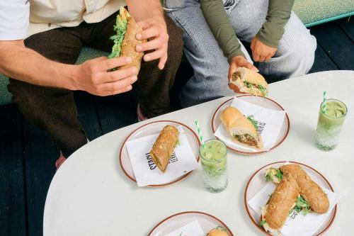 a group of people sitting at a table eating sandwiches at The Social Hub Amsterdam West in Amsterdam