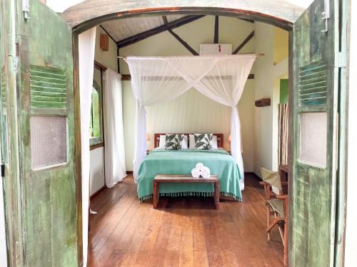 a bedroom with a green bed with a canopy at Casa Felina in Ilha de Boipeba