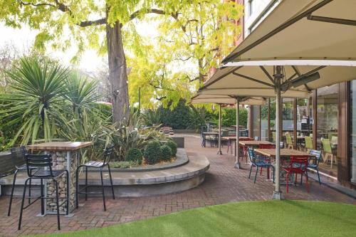 an outdoor patio with tables and chairs and umbrellas at DoubleTree by Hilton London - Hyde Park in London