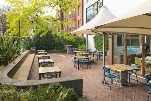an outdoor seating area with tables and chairs and umbrellas at DoubleTree by Hilton London - Hyde Park in London