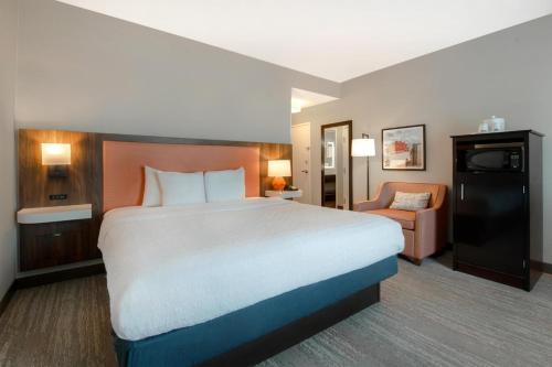 a hotel room with a large bed and a chair at Hampton Inn & Suites Harvey New Orleans Westbank in Harvey