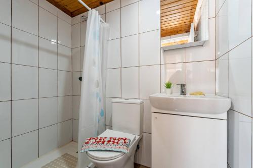 a white bathroom with a toilet and a sink at Wake up with the Sea Breeze- House with pool AP1 in Lavra