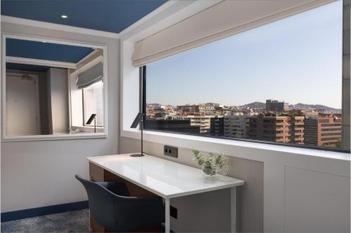 a room with a desk and a large window at Hilton Barcelona in Barcelona