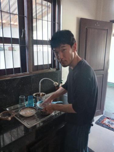 a man standing in a kitchen preparing food at Curly Hostel Negombo in Negombo