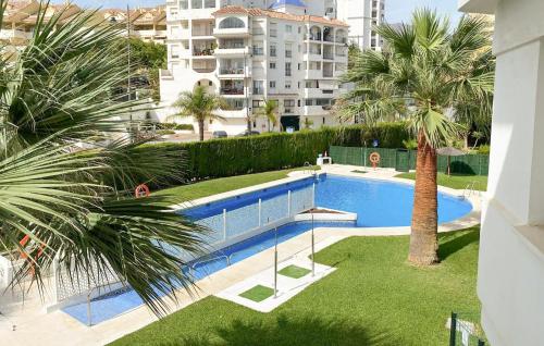 a swimming pool with a palm tree and a building at 2 Bedroom Lovely Apartment In Estepona in Estepona