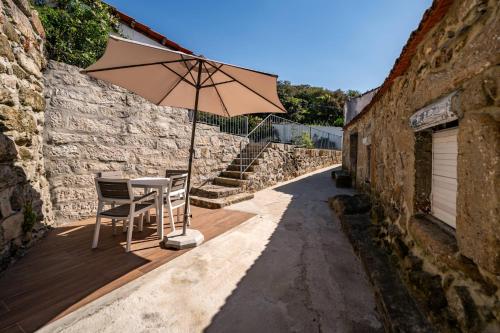 a table and chair with an umbrella on a wooden deck at RestOnDouro Oporto Studio in Valbom