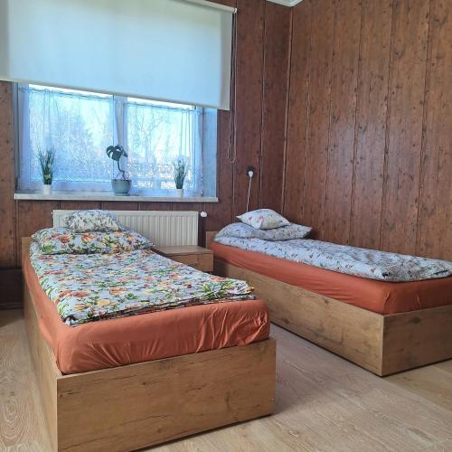 two beds in a room with wood paneled walls at Noclegi Arka in Osiek