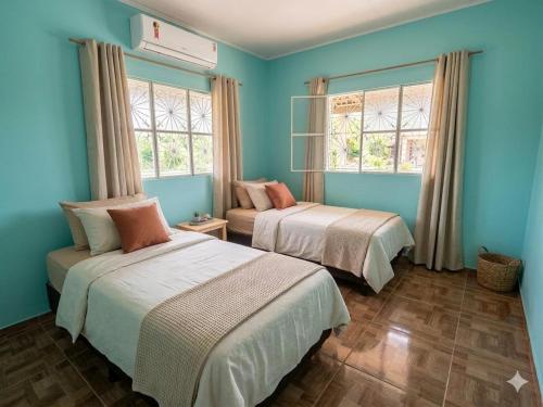 two beds in a room with blue walls and windows at Chácara Betel in Marechal Deodoro
