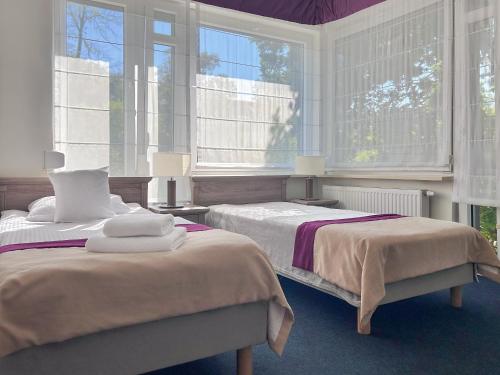 two beds in a room with two windows at WILla Medica in Poznań