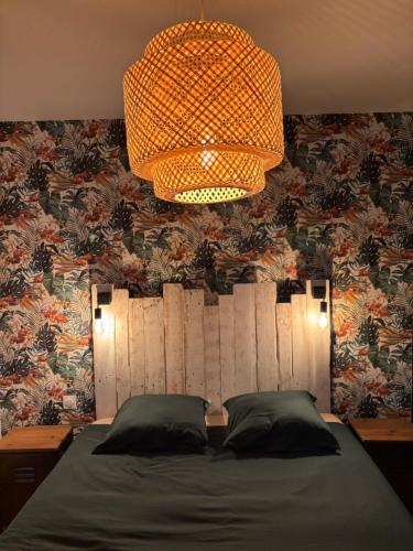 a bedroom with a bed and a chandelier at La Petite Maison in Arsy