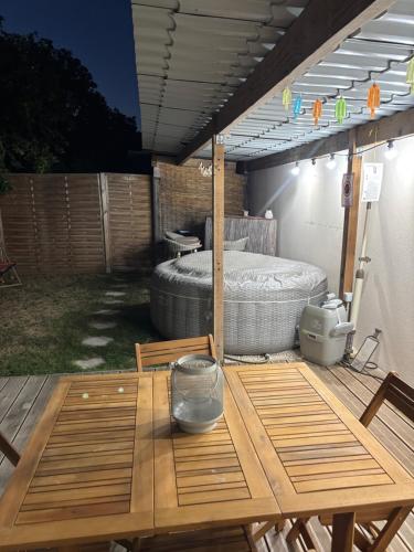 a patio with a table and a bed in a backyard at La Petite Maison in Arsy