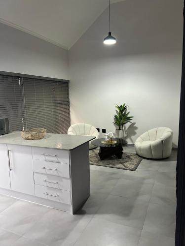 a white kitchen with two white chairs and a table at EHH Accommodation Hentiesbay in Hentiesbaai