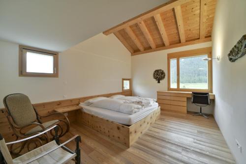 a bedroom with a bed and a desk and a chair at Chesa Pino - Madulain in Madulain