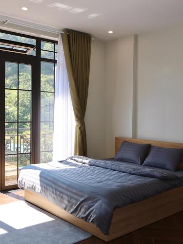 a bedroom with a bed and a large window at Prova Home in Da Lat