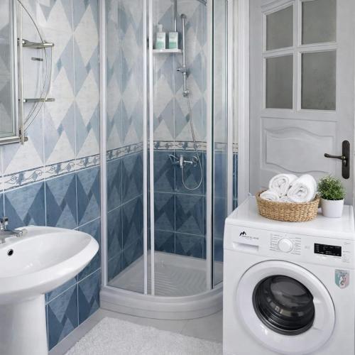 a bathroom with a shower and a washing machine at La Perle de Hergla Maison d Hotes in Harqalah