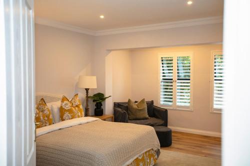 a bedroom with a bed and a chair and a window at Dornoch House, Gowrie Village in Nottingham Road