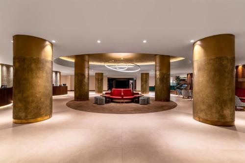 a lobby with columns and a red couch at Hilton Birmingham Metropole Hotel in Bickenhill