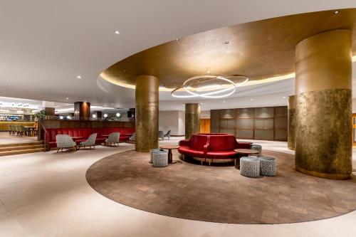 a lobby with a red couch and tables and chairs at Hilton Birmingham Metropole Hotel in Bickenhill