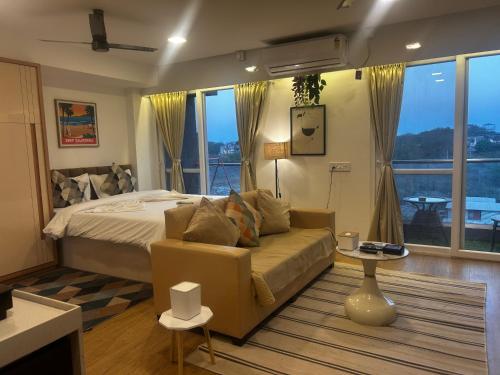 a bedroom with a bed and a couch and windows at Atelier Sol- ultra luxe aparthotel near airport in Pune