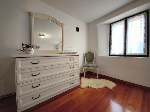a bedroom with a dresser with a mirror and a chair at La casa nel borgo in Cavaso del Tomba