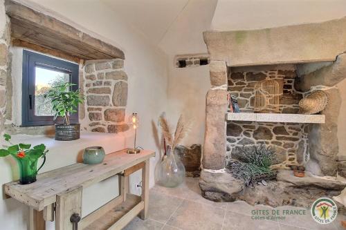a living room with a stone fireplace and a table at Kerguntuil in Pleumeur-Bodou