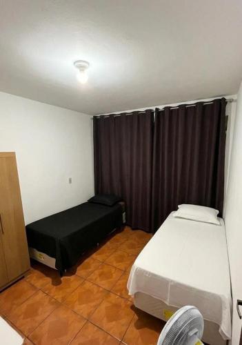 a small room with two beds and a window at Quarto individual Aconchego in Divinópolis