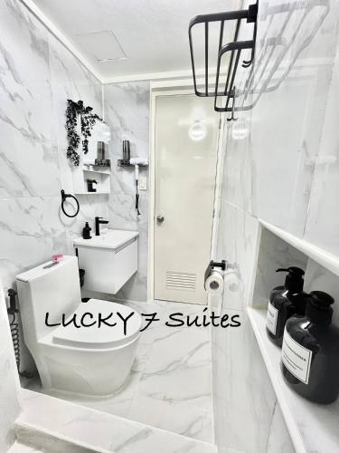 a white bathroom with a toilet and a shower at Welcome to lucky7suites in Manila