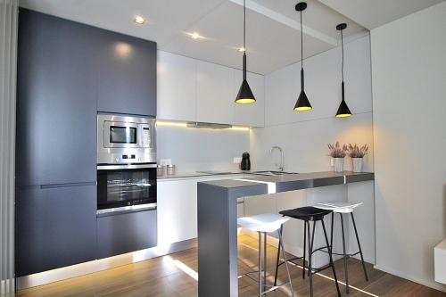 a kitchen with white cabinets and a counter with stools at RestOnDouro Oporto Flat in Valbom