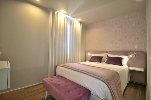 a bedroom with a large bed with a pink stool at RestOnDouro Oporto Flat in Valbom