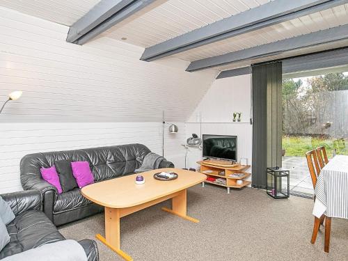 a living room with a black leather couch and a table at 6 person holiday home in Ringkøbing in Ringkøbing