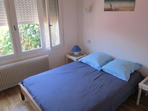 a bedroom with a bed with blue sheets and two windows at Havre de paix au bord de létang de Thau avec vue-magnifiques couchers de soleil-et accès direct et privé à l'eau-possibilité de se garer gratuitement dans la rue in Sète