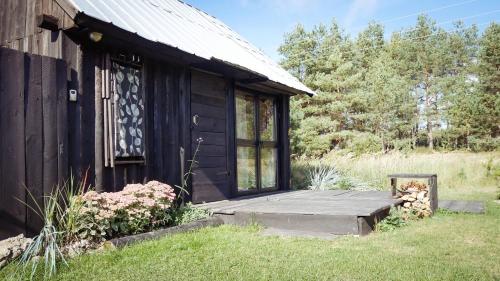 a small black building with a wooden porch at Drewutnia nad Hańczą in Sernetki