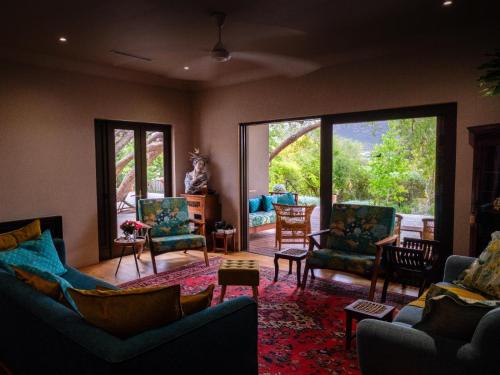 a living room with couches and chairs and a large window at Kamala Karoo Sanctuary in Barrydale