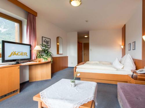 Habitación de hotel con cama y TV en Landhotel Jäger TOP, en Wildermieming