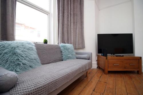 a living room with a couch and a flat screen tv at Cathedral House by Tŷ SA in Newport