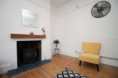 a living room with a yellow chair and a fireplace at Cathedral House by Tŷ SA in Newport