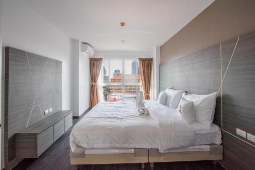 a bedroom with a large bed with a large window at Dwija Hotel & Suite in Pattaya South