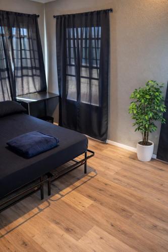 a bedroom with a bed and a plant on a wooden floor at Hoover Vibe Near Public Transportation in Los Angeles