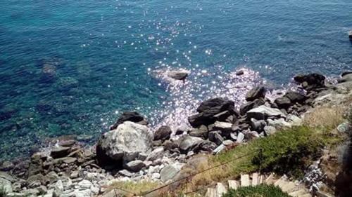 a large group of rocks on the shore of the water at Delfini in Akhladherí