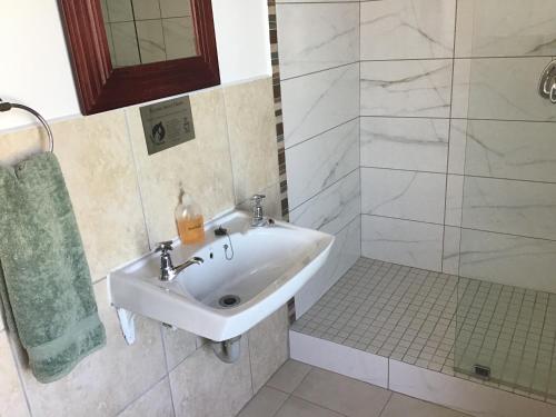 a white bathroom with a sink and a shower at Knysna Manor House in Knysna