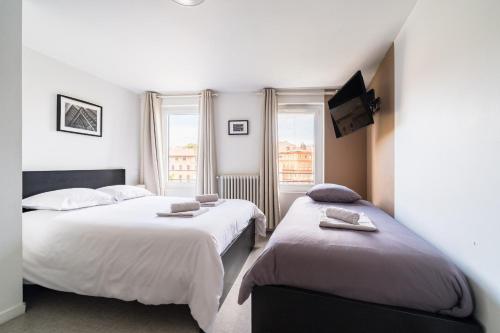 a bedroom with two beds and a tv on the wall at Premier Acte - Chambre Spacieuse Sur Les Allées in Toulouse